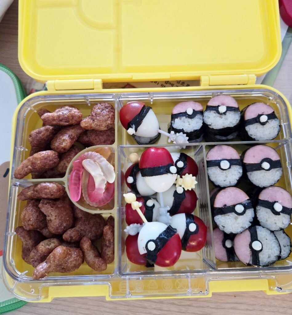 소세지 김밥과 메추리알 방울토마토로 만든 포켓몬볼 모양, 지렁이 젤리, 포켓몬초코 과자가 담긴 리틀그립 야미박스 노란색 도시락 통